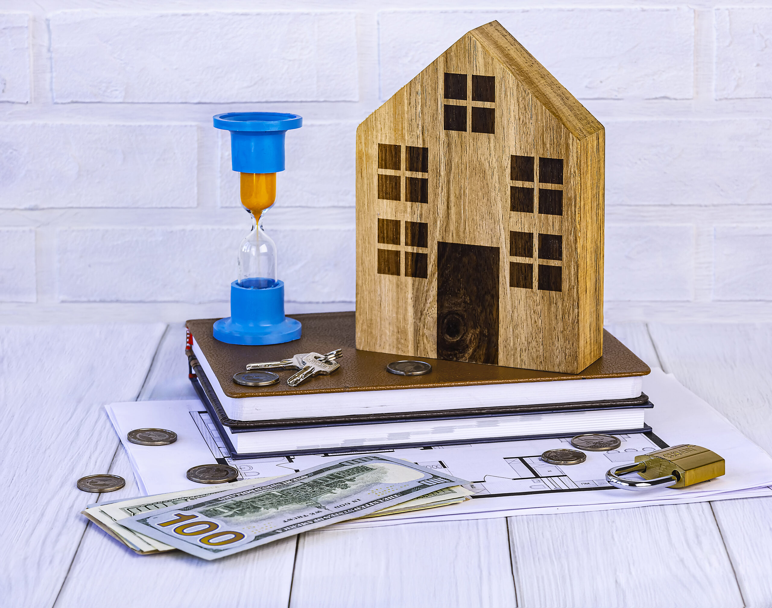 Home loan concept. Wooden house, hourglass, house keys, dollars, documents